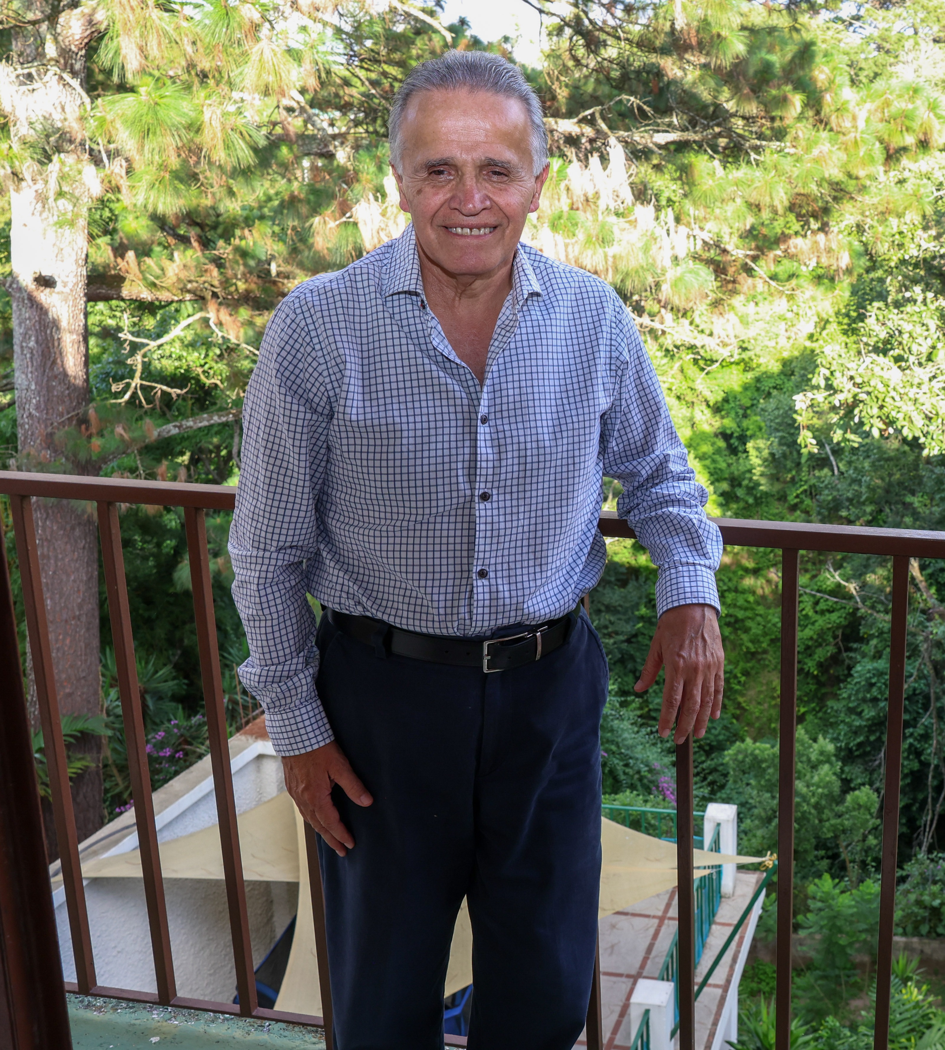 Dr. Fernando Estrada de pie, sonriendo, rodeado de vegetación