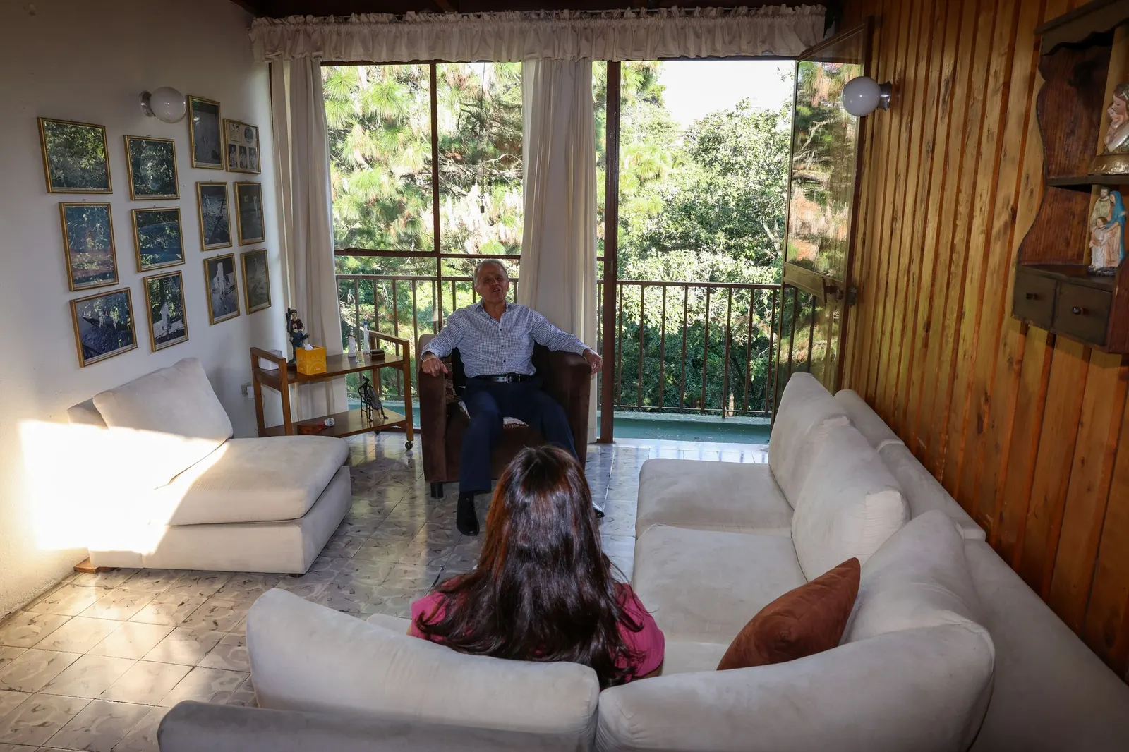 Dr. Fernando Estrada conversando con una paciente durante una sesión, ambos sentados frente a frente junto a un balcón con vista a los árboles